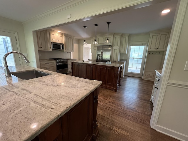 kitchen featuring stainless steel appliances, dark wood-type flooring, a sink, and a kitchen island