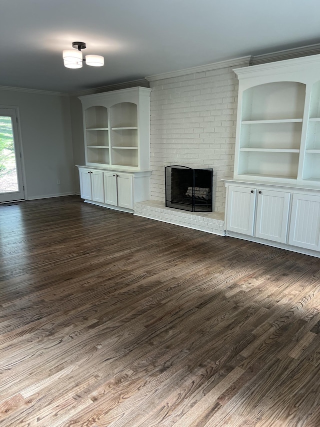 unfurnished living room with dark wood-style floors, baseboards, ornamental molding, and a brick fireplace
