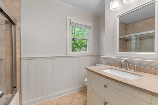 full bathroom with tile patterned flooring, toilet, vanity, crown molding, and wainscoting