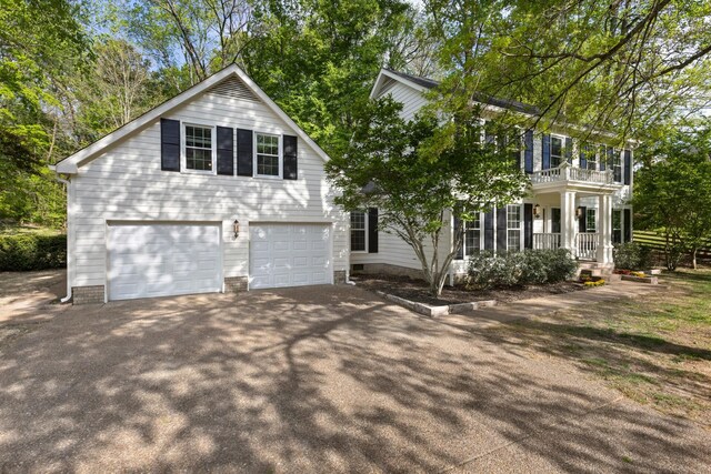 view of front of property featuring an attached garage, aphalt driveway, a porch, and a balcony