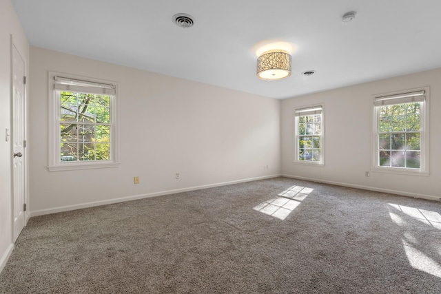 carpeted empty room featuring baseboards and visible vents