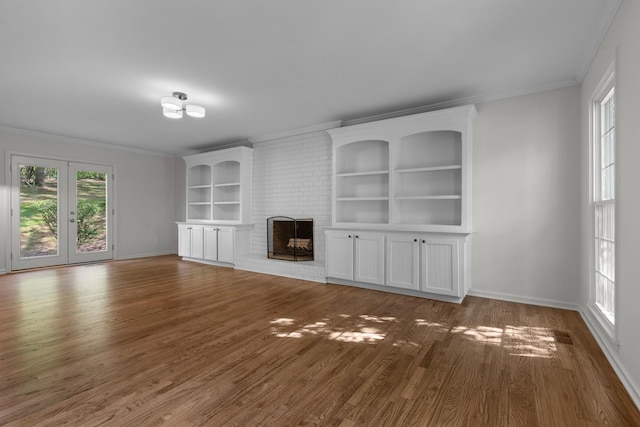 unfurnished living room with a fireplace, wood finished floors, crown molding, and baseboards