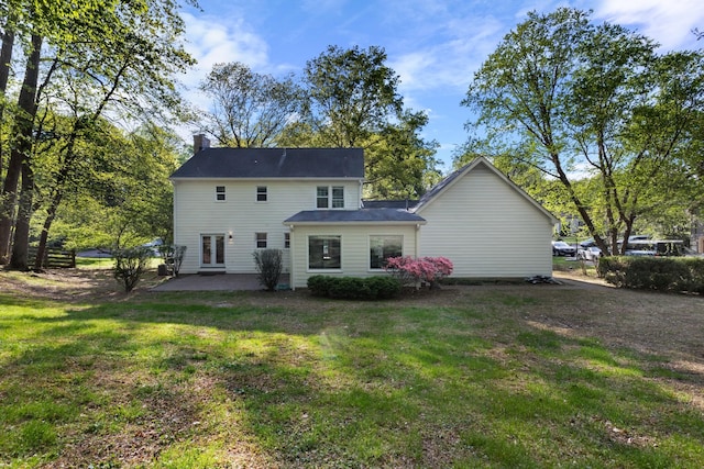 back of property with a yard, a chimney, and a patio area