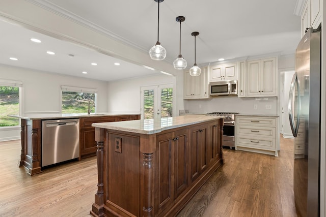 kitchen featuring light wood-style flooring, appliances with stainless steel finishes, a center island, and a sink