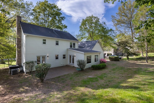 back of house with a chimney, cooling unit, french doors, a patio, and a lawn