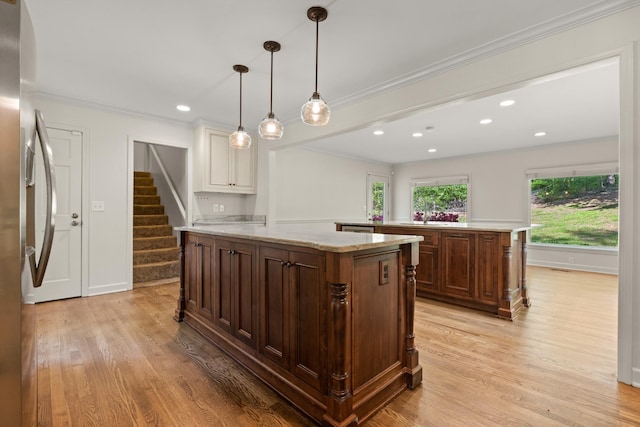 kitchen with light wood finished floors, freestanding refrigerator, a large island, and crown molding