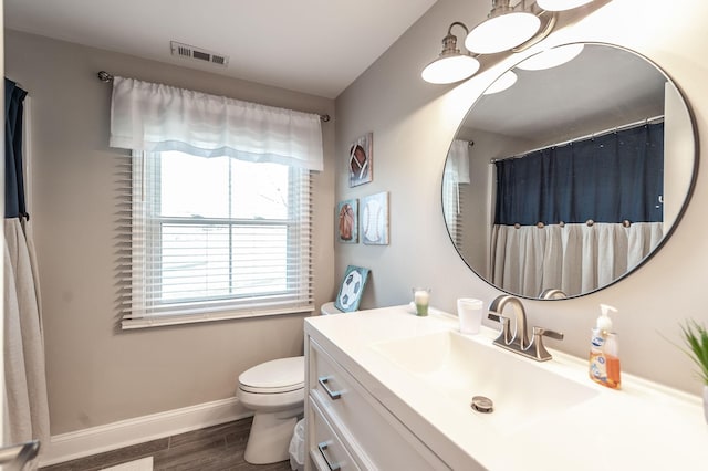 bathroom featuring vanity, toilet, visible vents, baseboards, and wood finished floors