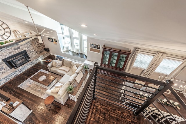 living room featuring recessed lighting, wood finished floors, ceiling fan, a stone fireplace, and baseboards