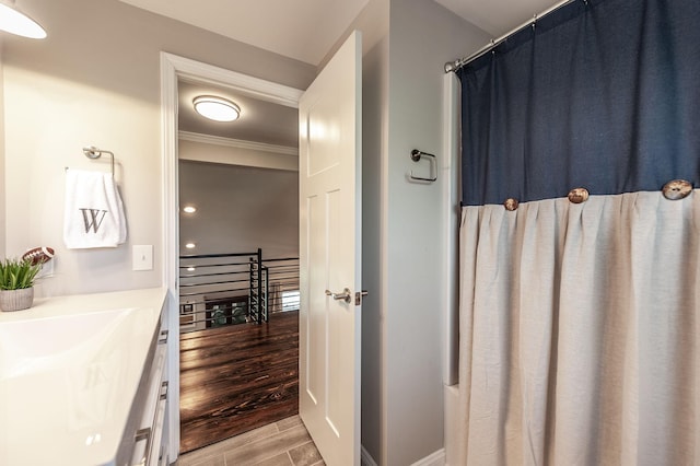 bathroom with crown molding, a shower with curtain, wood tiled floor, baseboards, and vanity
