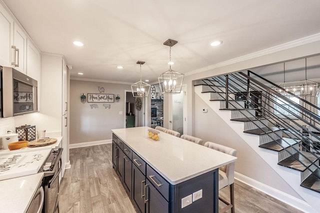 kitchen with a breakfast bar area, white cabinetry, crown molding, stainless steel appliances, and baseboards