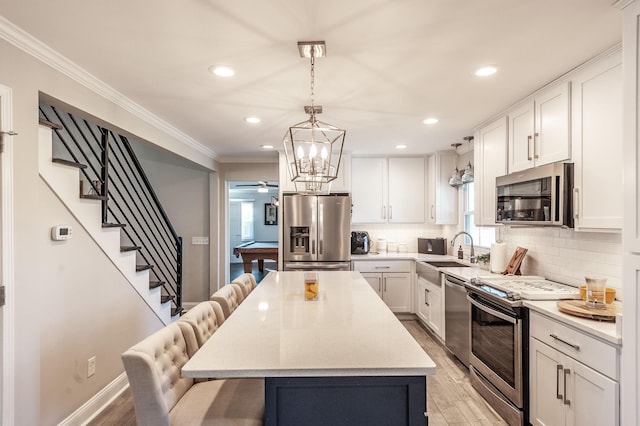 kitchen with appliances with stainless steel finishes, a kitchen breakfast bar, light wood finished floors, and a sink