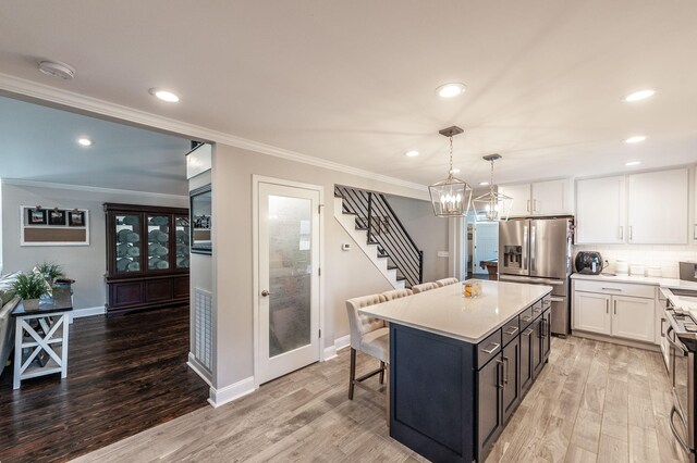 kitchen featuring crown molding, white cabinets, appliances with stainless steel finishes, and light wood-type flooring