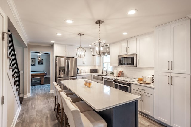 kitchen featuring ornamental molding, recessed lighting, a breakfast bar, and appliances with stainless steel finishes