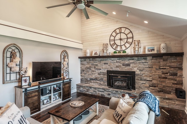 living room featuring wooden walls, a ceiling fan, a stone fireplace, and wood finished floors