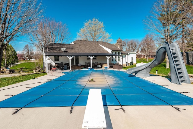 view of swimming pool with a covered pool, a water slide, a patio area, a diving board, and an outdoor living space