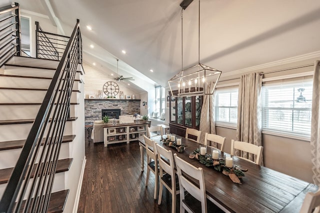 dining area featuring stairs, ceiling fan with notable chandelier, a stone fireplace, dark wood-style floors, and lofted ceiling