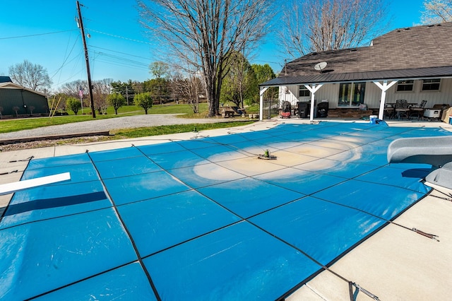 view of pool featuring a covered pool, a diving board, and a patio area