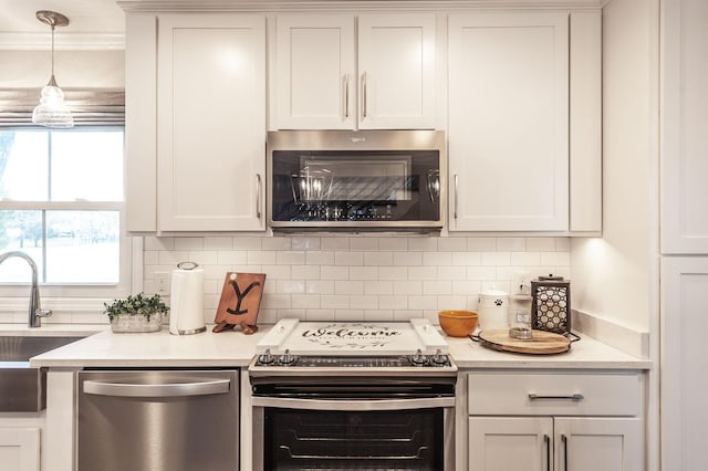 kitchen with decorative backsplash, appliances with stainless steel finishes, light countertops, white cabinetry, and pendant lighting