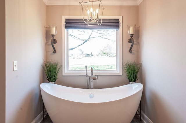 bathroom with a freestanding tub, an inviting chandelier, crown molding, and baseboards