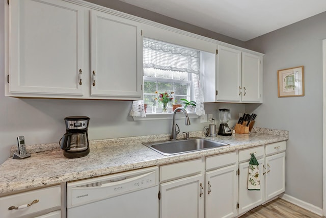 kitchen with light countertops, light wood-style flooring, dishwasher, white cabinetry, and a sink