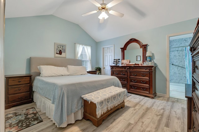 bedroom featuring vaulted ceiling, light wood-style flooring, ensuite bathroom, and a ceiling fan