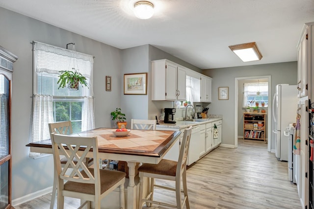 dining space featuring baseboards and light wood-style flooring