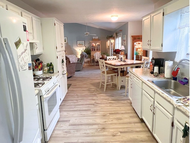 kitchen featuring light countertops, a healthy amount of sunlight, white appliances, a sink, and light wood-style floors