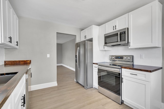 832 Richardson St, Clarksville, TN 37040 - kitchen featuring stainless steel appliances, baseboards, light wood-type flooring, white cabinetry, and backsplash