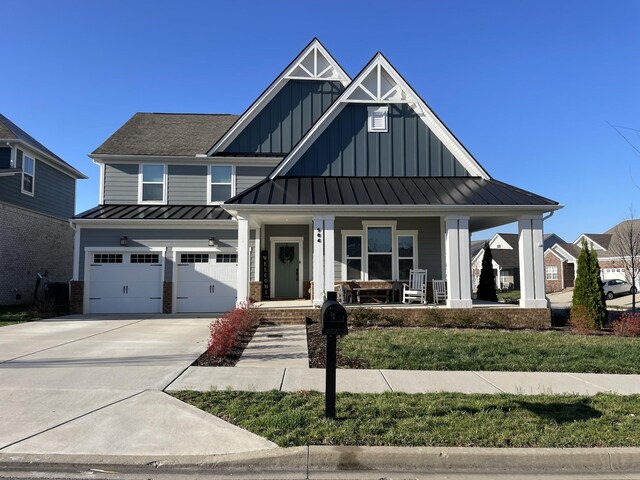modern farmhouse featuring concrete driveway, a standing seam roof, metal roof, an attached garage, and covered porch