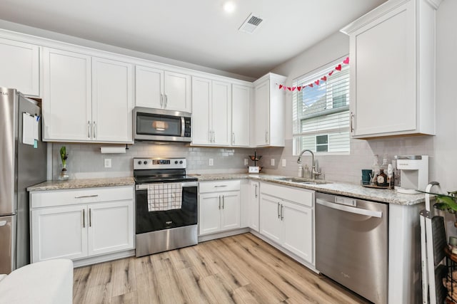 923 Long Train Aly, Antioch, TN 37013 - kitchen featuring a sink, white cabinetry, appliances with stainless steel finishes, light wood-style floors, and decorative backsplash