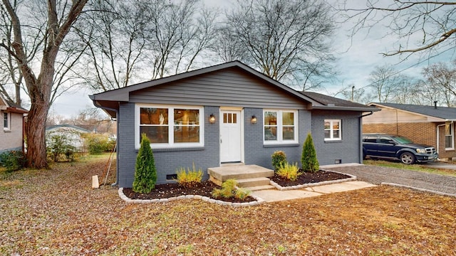 bungalow-style home featuring crawl space, driveway, and brick siding
