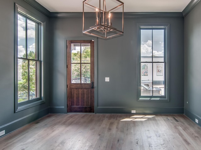 foyer with an inviting chandelier, crown molding, wood finished floors, and a healthy amount of sunlight