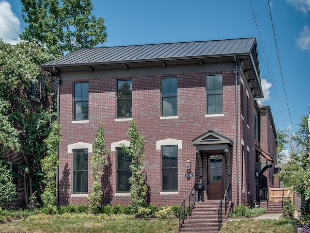 view of front of home featuring metal roof, a standing seam roof, and brick siding
