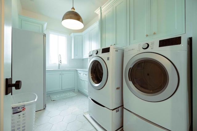 laundry room with a sink, cabinet space, washer and dryer, and light tile patterned flooring