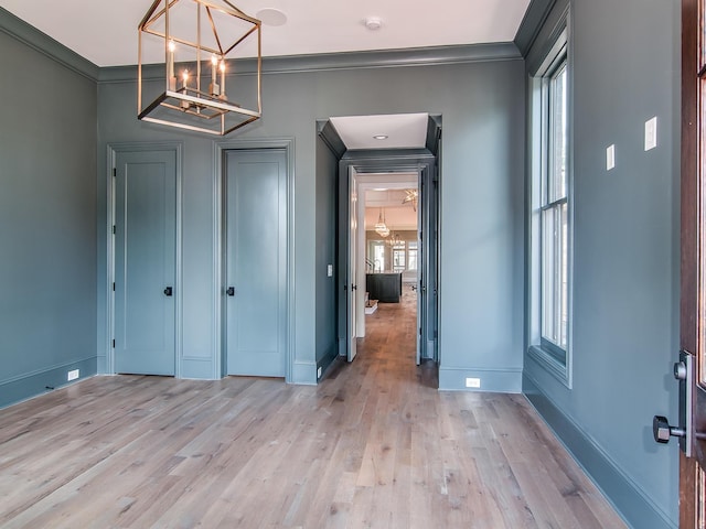 entryway featuring baseboards, ornamental molding, a chandelier, and light wood-type flooring