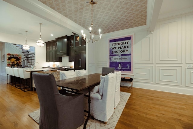 dining room with light wood-type flooring, stairway, a decorative wall, and a chandelier