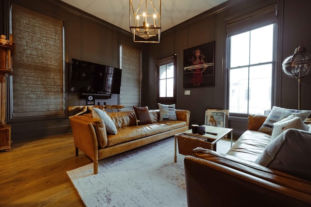 living area featuring an inviting chandelier, wood finished floors, ornamental molding, and a wealth of natural light