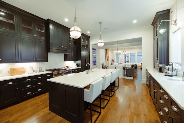 kitchen with light countertops, a sink, a chandelier, a breakfast bar, and light wood-style floors