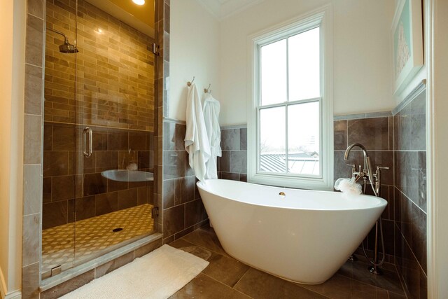 full bath with tile patterned flooring, a freestanding tub, a stall shower, and a healthy amount of sunlight