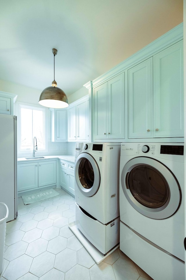 washroom with light tile patterned floors, a sink, cabinet space, and washer and clothes dryer