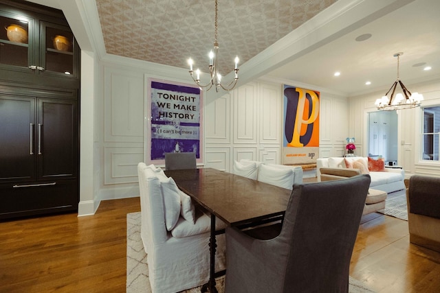 dining space with a notable chandelier, crown molding, wood finished floors, a decorative wall, and recessed lighting