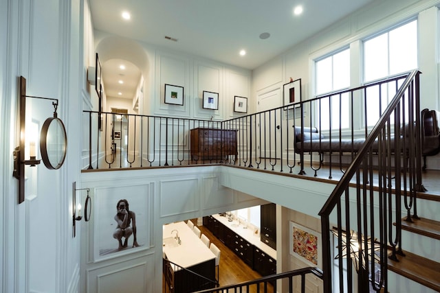 stairway featuring visible vents, recessed lighting, arched walkways, and a decorative wall