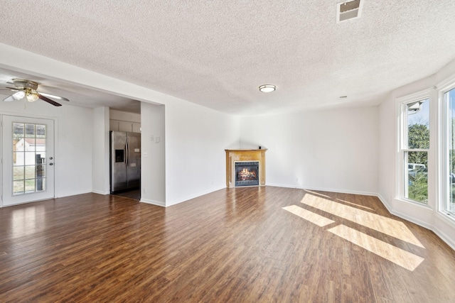 3049 Fieldstone Dr, Antioch, TN 37013 - unfurnished living room featuring a warm lit fireplace, dark wood-style floors, visible vents, and a wealth of natural light