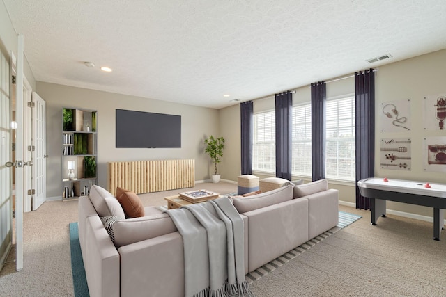 living area featuring visible vents, carpet floors, and a textured ceiling