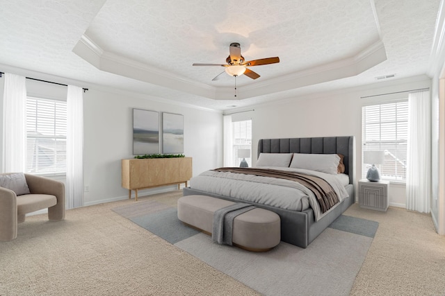 bedroom with light carpet, a tray ceiling, and ornamental molding