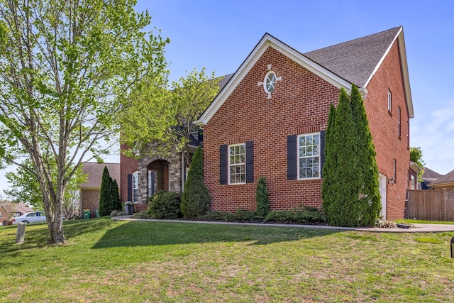view of front facade with fence, a front lawn, and brick siding