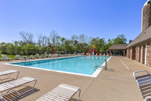 community pool featuring fence, a patio area, and playground community