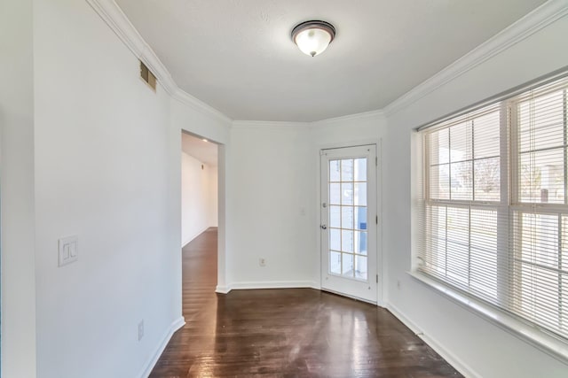 unfurnished room with visible vents, crown molding, baseboards, and wood finished floors