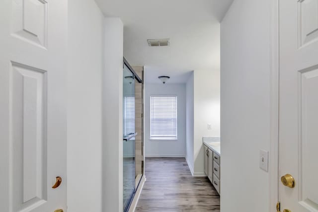 bathroom with vanity, baseboards, a shower stall, visible vents, and wood finished floors
