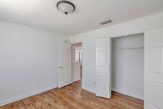unfurnished bedroom with baseboards, visible vents, a closet, and light wood-type flooring